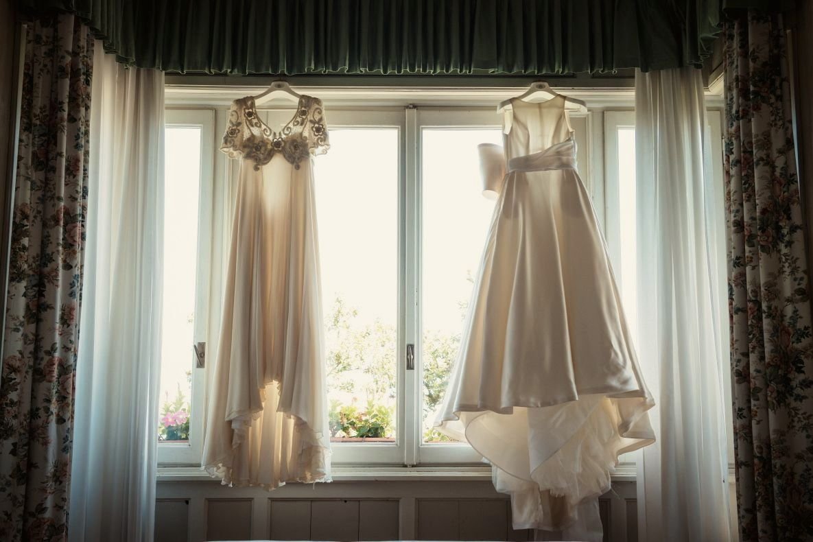 Due abiti da sposa Maison Bourelly appesi alla finestra, in controluce