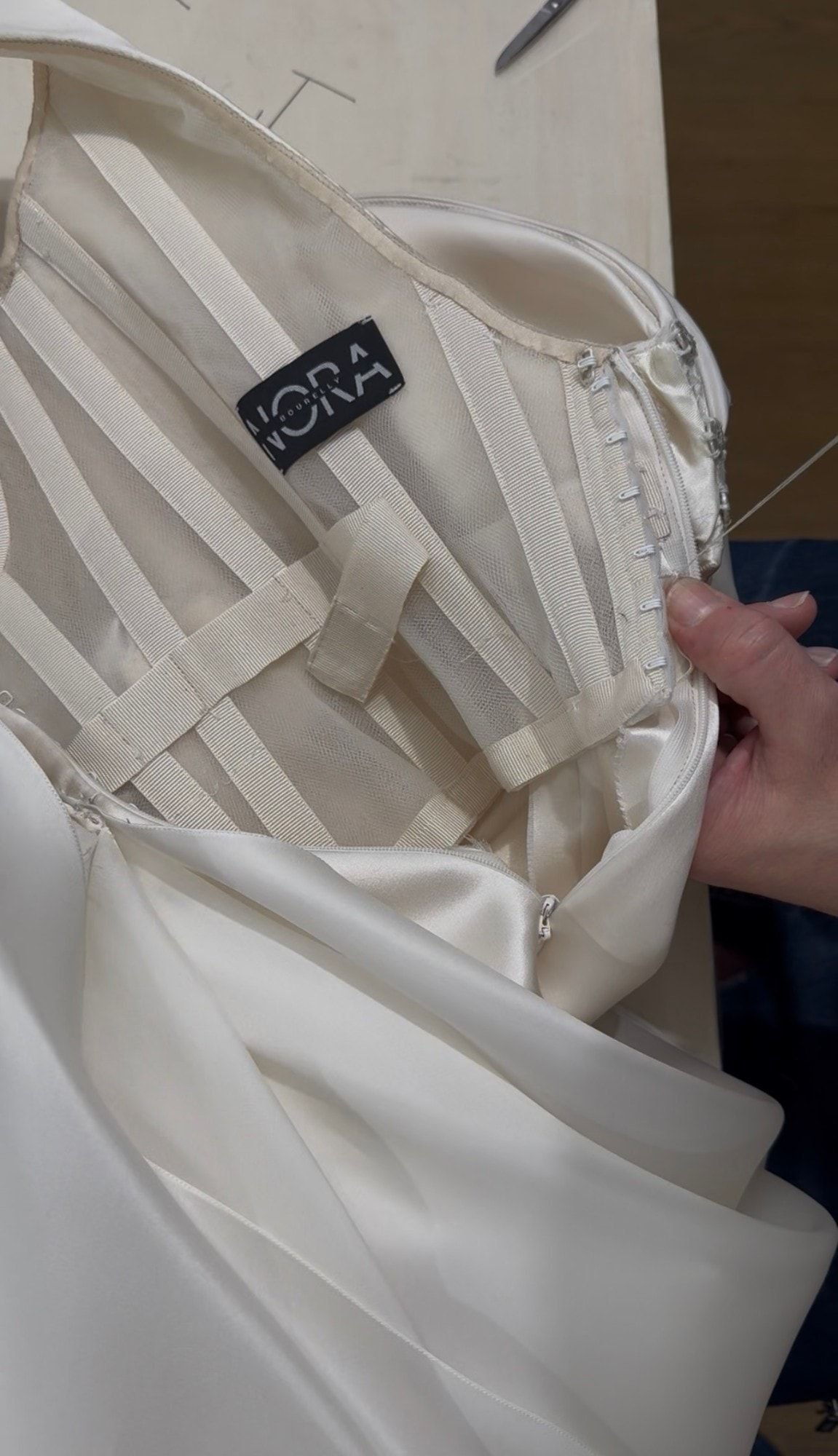 L’interno di un abito da sposa: la struttura in gros-grain e tulle, i ganci cuciti a mano e l’etichetta Nora Bourelly