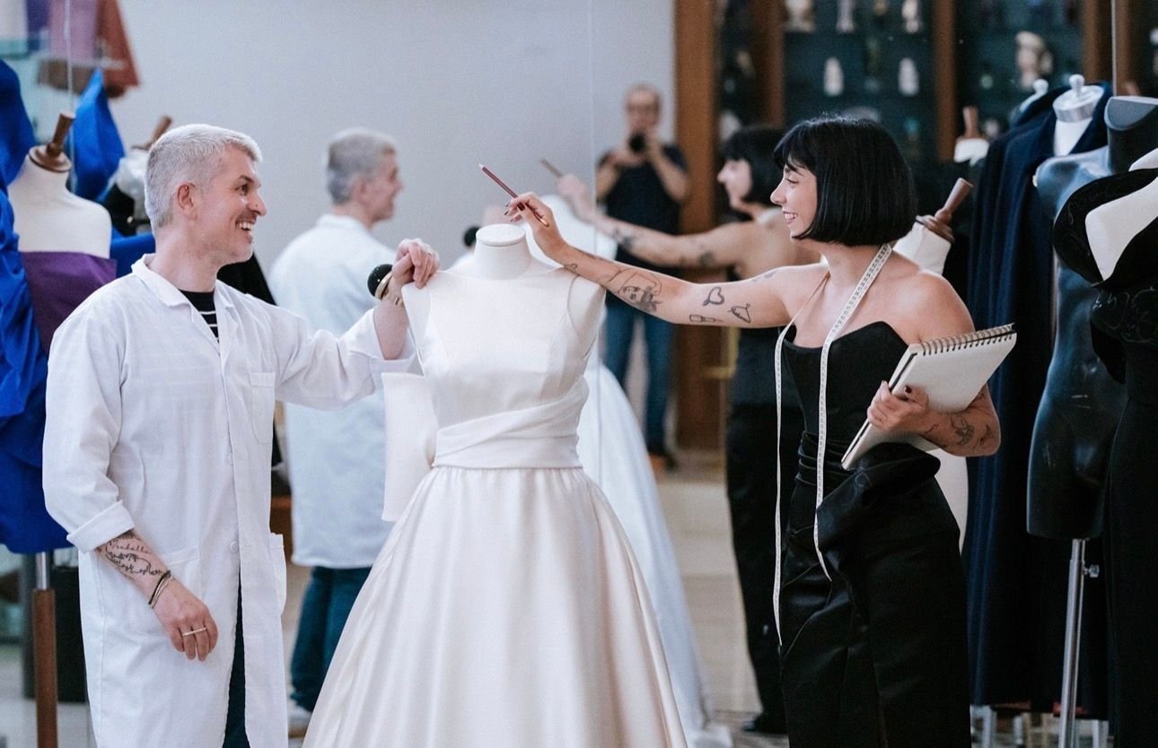 La fondatrice disegna sul blocco accanto a un abito da sposa, in atelier