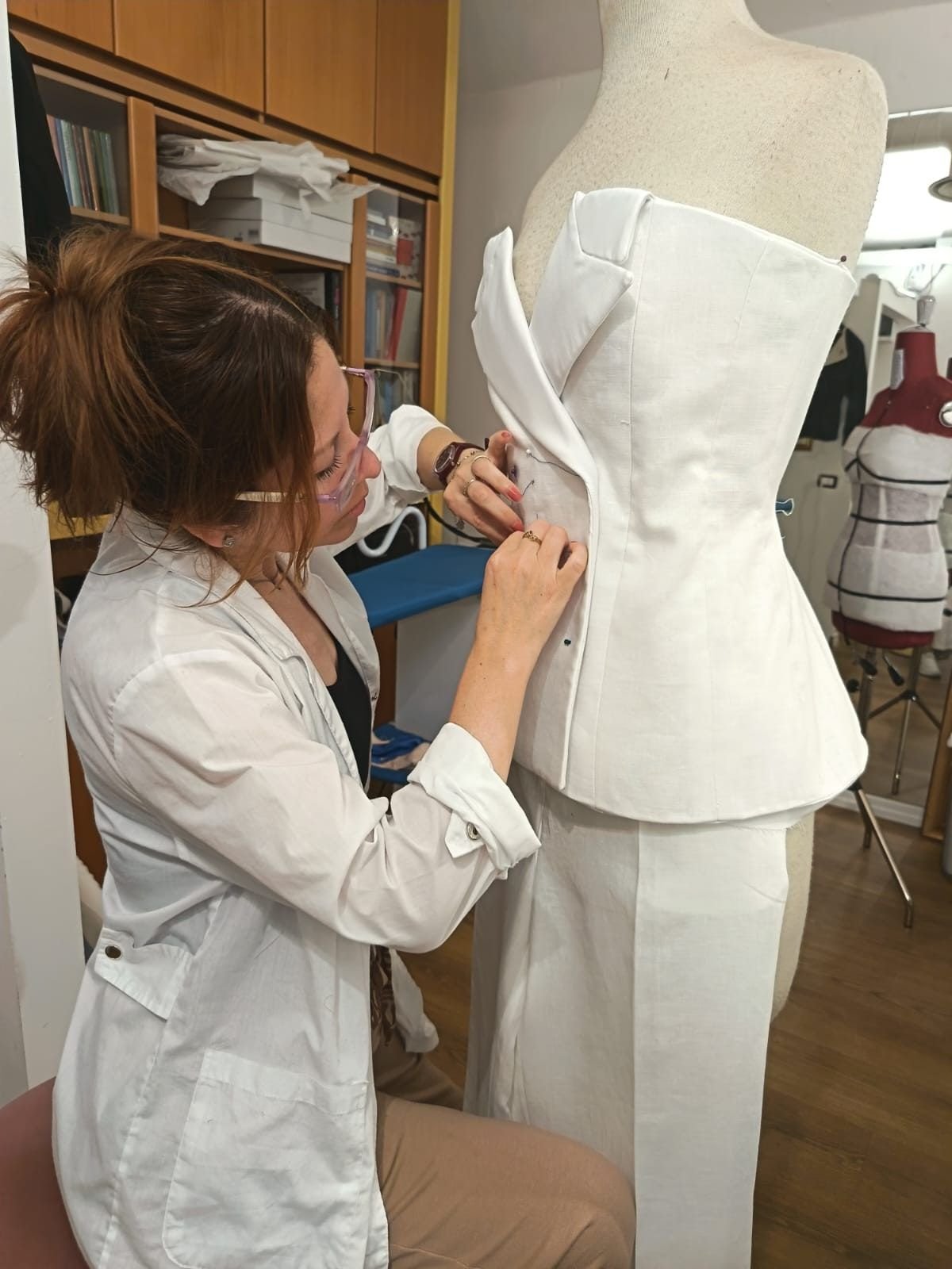 Una sarta appunta a mano la tela di un bustier sul manichino